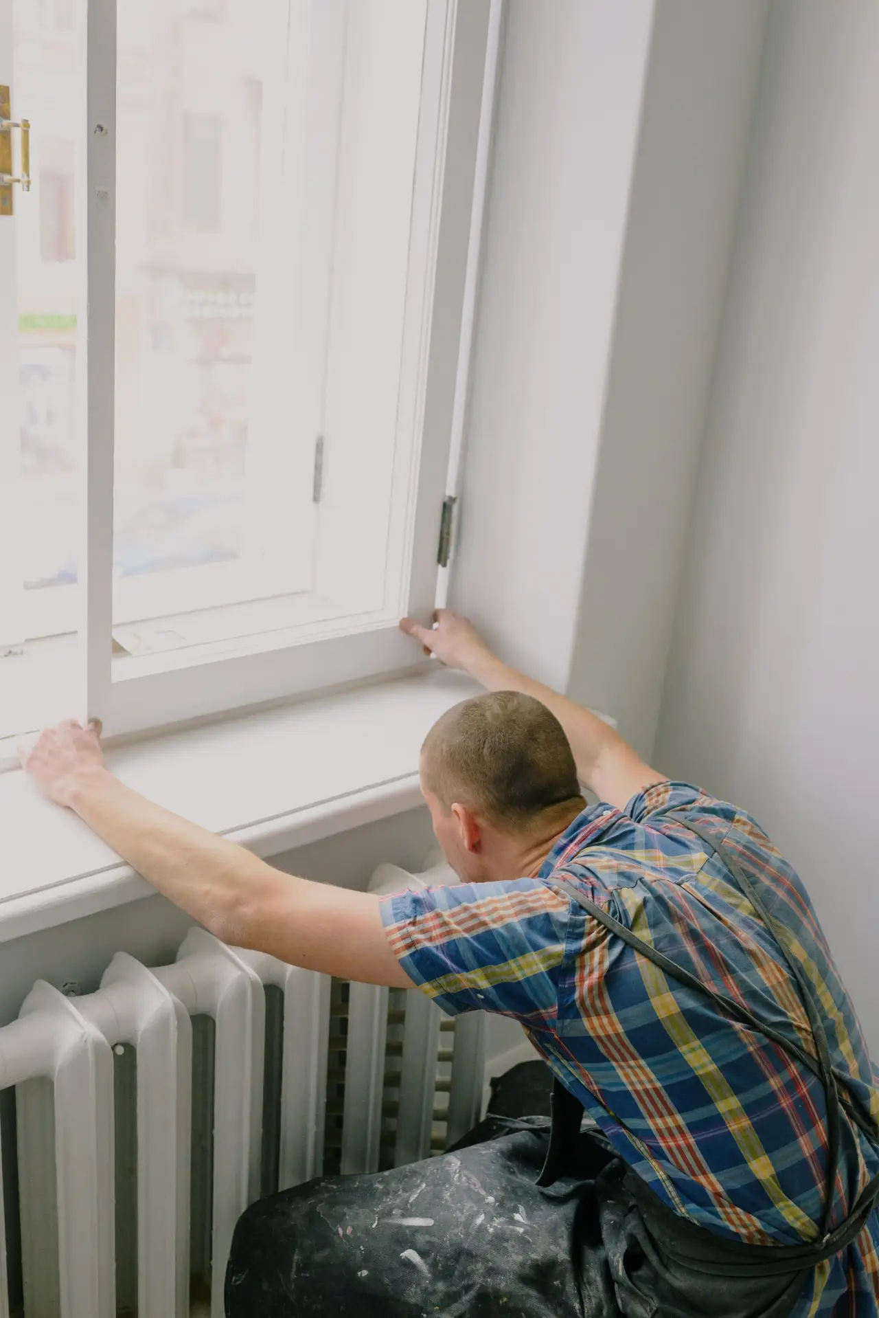 Ein Handwerker baut in einem Zimmer, das gerade saniert wird, ein neues Fenster ein