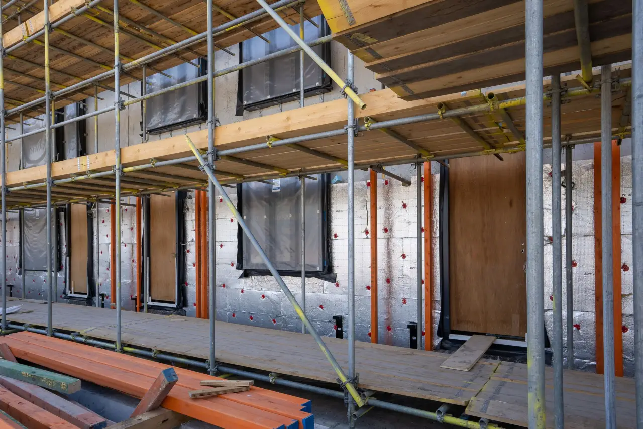 Isolation thermique de façade en cours sur une maison individuelle, à côté d'un échafaudage